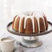 A Nordic Ware fluted bundt cake with white icing on a plate.