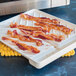 A white Nordic Ware plastic tray with bacon on it.