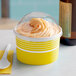 A yellow Choice paper cup with a dome lid filled with ice cream on a counter.