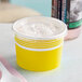 A close-up of a yellow Choice paper frozen yogurt cup with a flat white lid.