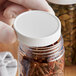 A person holding a jar of spices with a white polypropylene cap.