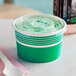 A close-up of a green Choice paper container with a flat lid.