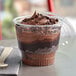 A chocolate mousse dessert in a Choice clear plastic cup with a spoon.