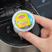 A hand holding a small white plastic container with a yellow and blue round label for Lipton Southern Sweet Iced Tea K-Cup Pods.