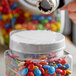 A clear plastic shrink band on a plastic container of colorful candies with a white cap.
