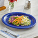 An Acopa blue melamine platter with a salad on it and a fork.