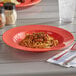 An Acopa Foundations orange melamine bowl filled with spaghetti and a fork on a table.
