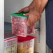 A person holding a Cambro FreshPro square polypropylene container of strawberries.