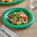 An Acopa Foundations green melamine plate with a salad on it.