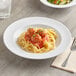 A white Acopa Foundations melamine pasta bowl filled with spaghetti and meatballs with a side salad.