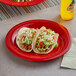 Two red Acopa Foundations wide rim melamine plates with tacos on them.