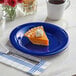 A piece of pie on an Acopa Foundations blue melamine plate with a cup of coffee and flowers.