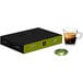 A black Nespresso Professional Leggero coffee box with a green lid on a table with a glass of brown coffee.