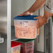 A person holding a Cambro FreshPro translucent square polypropylene container with food in it.