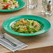 A plate of pasta with green salad in a melamine bowl on a table.