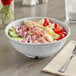 A white Acopa Foundations melamine salad bowl filled with vegetables on a table in a salad bar.
