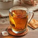 A glass cup of Harney & Sons decaf Ceylon tea on a coaster with a tea bag.