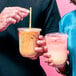 Two people holding Tossware Natural plastic cups with drinks.