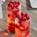 Two glasses of raspberries and ice.