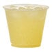 A Tossware plastic cup with yellow liquid in it.