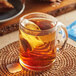 A Harney & Sons Orange Pekoe tea bag in a glass mug on a table.