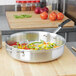 A Vollrath Wear-Ever aluminum saute pan with vegetables cooking in it.