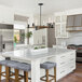A kitchen island with a white counter and stools, one with a cushion.