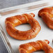 A baking sheet of Eastern Standard Provisions Wheelhouse Soft Pretzels with a hole in the middle.