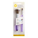 A package containing two Wilton cake decorating brushes with a purple handle.