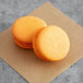 Two Coco Bakery mango passionfruit macarons on a brown surface.
