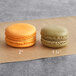 Two Coco Bakery Mango Passionfruit macarons on a piece of paper.