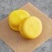 Two Coco Bakery Meyer lemon macarons on brown paper.