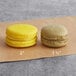 Two Coco Bakery Meyer Lemon macarons on brown paper.