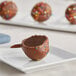 A chocolate cake pop with sprinkles on a plate.