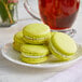 A white plate with three green Coco Bakery pistachio macarons.