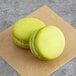 Two Coco Bakery pistachio macarons on brown paper.