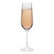 A Tossware Reserve Go-To plastic flute glass filled with champagne with bubbles.