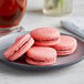 A plate with three Coco Bakery raspberry macarons.