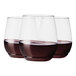 Three Tossware plastic wine glasses filled with red wine.