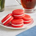 A white plate with a stack of red and white Coco Bakery Red Velvet Macarons.