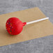 A red and white Coco Bakery Red Velvet cake pop with sprinkles on it.