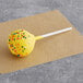 A yellow Coco Bakery lemon cake pop with sprinkles on top.