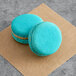 Two blue Coco Bakery salted caramel macarons on a brown surface.