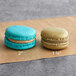 A blue and brown Coco Bakery macaron on brown paper.