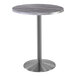 A Holland Bar Stool round table with a metal base and a round Greystone top.