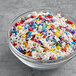 A bowl filled with Supernatural Rainbow Starfetti sprinkle mix, featuring colorful stars.