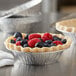A Baker's Mark foil tart pan with a pie and berries inside.