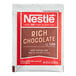 A close up of a red and white Nestle Rich Chocolate Hot Cocoa mix packet with white text.