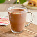A glass mug of Nestle hot chocolate on a cutting board.