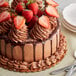 A chocolate cake with strawberries on top displayed on a table.